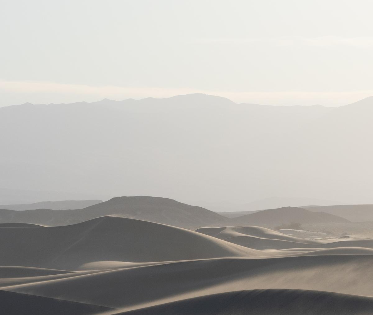 Sand dunes fading into hazy mountains