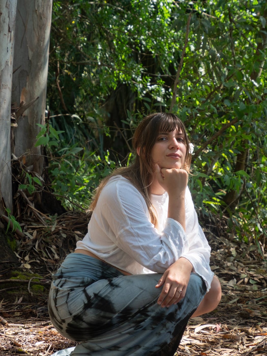 Leyla Fıratlı crouched in a grove among the trees