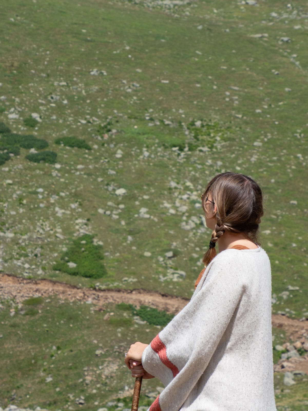 Leyla seen from behind, hair in a braid, looking out over a green hillside